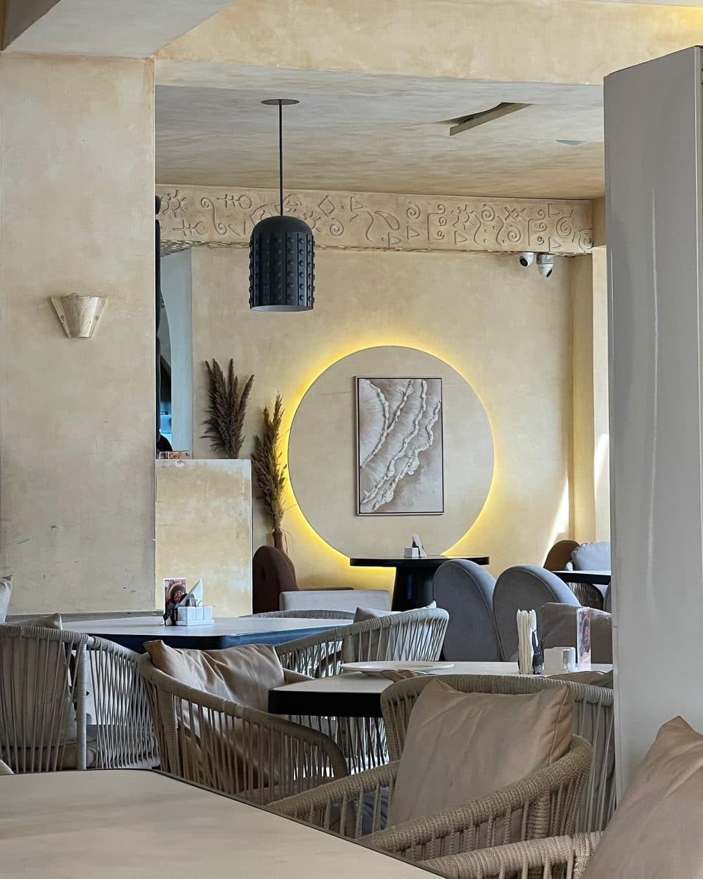 Backlit plaster niche and pendant above rattan seating