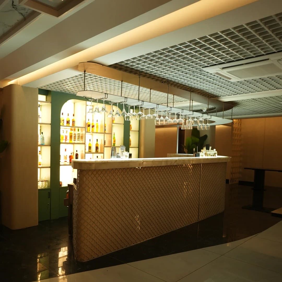 Backlit bar with hanging stemware and a green spirit shelf